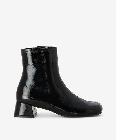 Black patent leather ankle boots by Sempre Di. It features a paneled upper with side zip closure, low block heel, and a round toe.