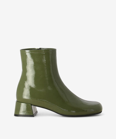 Green patent leather ankle boots by Sempre Di. It features a paneled upper with side zip closure, low block heel, and a round toe.