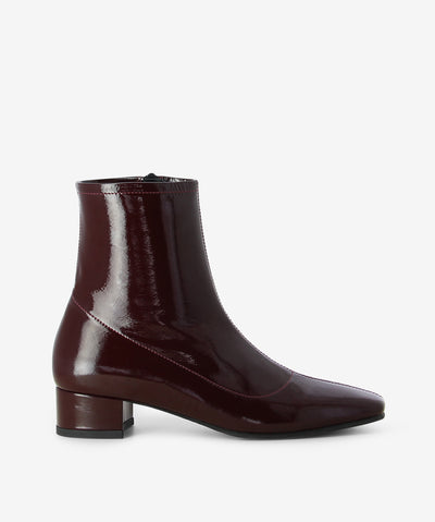 Deep red patent leather ankle boots by Sempre Di. It features a paneled upper with side zip closure, low block heel, and a chisel toe.