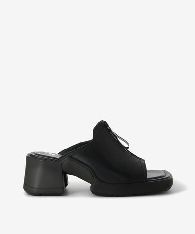 Black leather mule by Miista. A slip-on style and features a reflective zip pull upper, a medium block heel and a square toe.