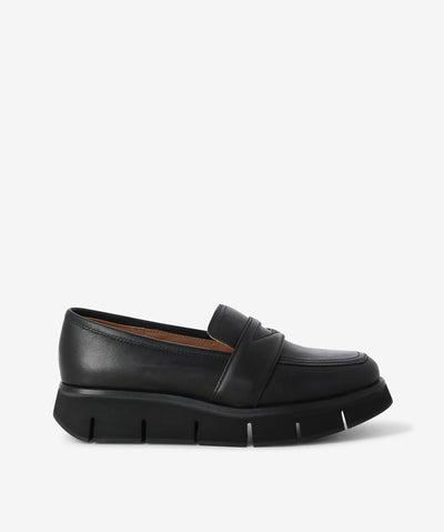 Black leather platform loafers by Alfie & Evie. It is a slip on style and features a chunky platform sole, and a soft square toe.