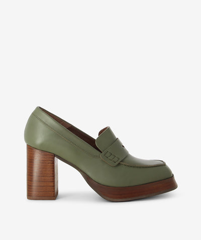 A classic penny silhouette dusty olive leather heeled loafers by Alohas. A slip-on style features a wooden block heel and a square toe.
