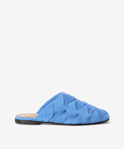 Blue suede mules by 2 Baia Vista. It is a slip-on style with an enclosed upper that features super soft interwoven suede as its upper, a flat sole, and a square toe.