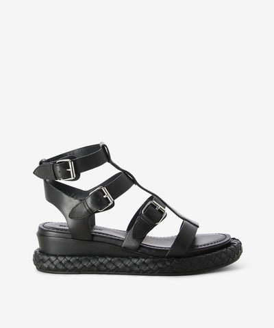 A black leather roman style sandal by Elvio Zanon. It has three buckle fastenings and features a woven platform sandal and an open round toe.