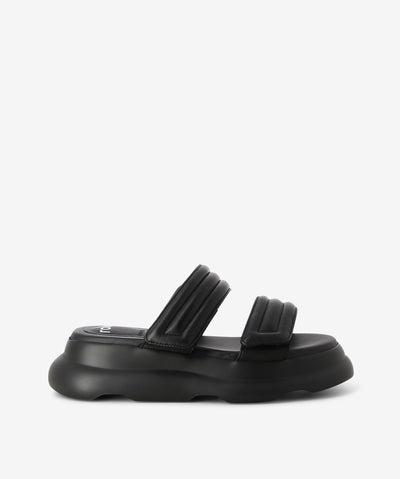 Black leather slides by Rollie. It is a slip-on style that features two adjustable velcro straps as its upper, a platform sole, and a round toe. 