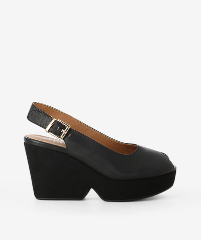 Black leather platform wedges by Alfie & Evie. It features an adjustable pin-buckle strap, chunky platform wedge, and a round peep toe.