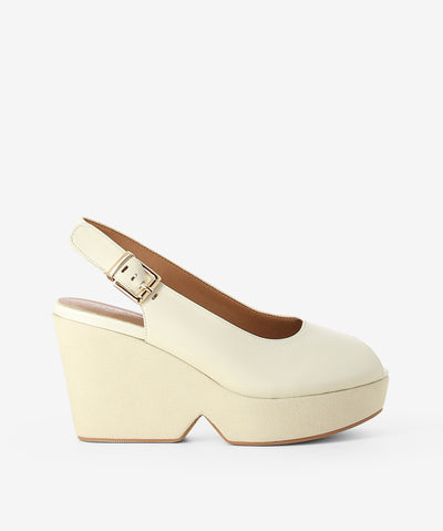 Cream leather platform wedges by Alfie & Evie. It features an adjustable pin-buckle strap, chunky platform wedge, and a round peep toe.