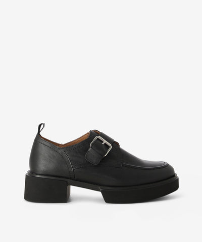 Black leather platform loafers by Alfie & Evie. It features front and back platforms, adjustable cross-foot pin-buckle strap, and a soft square toe.