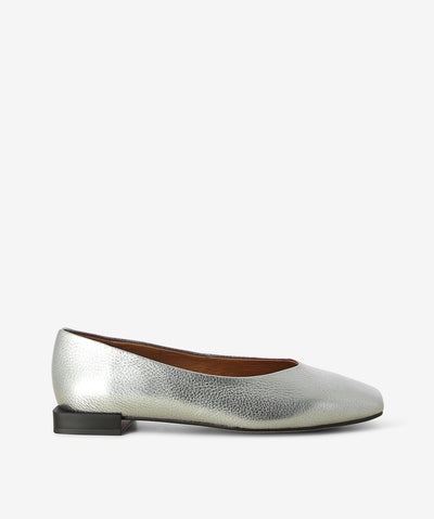 Silver metallic flats by Neo. It is a slip on style and features a low square heel, textured metallic upper, and a chisel toe.
