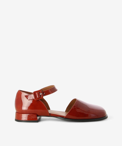 Red patent leather flats by Neo. It features a low block heel, adjustable pin-buckle strap, and an enclosed soft square toe.