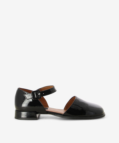 Black patent leather flats by Neo. It features a low block heel, adjustable pin-buckle strap, and an enclosed soft square toe.