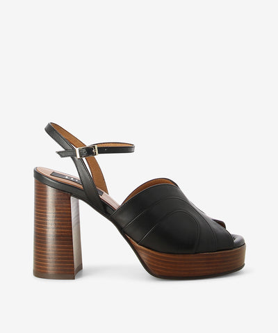 Black leather platform leather by Neo. It has a layered geometric leather upper, and features a block heel and front platform, adjustable pin-buckle strap, and a round toe.