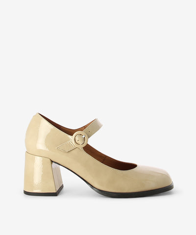 Beige crinkle patent leather Mary Jane heels by Neo. It features a block heel, adjustable pin-buckle strap, and a soft square toe.
