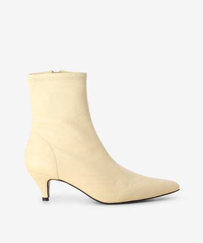 Off-white leather ankle boots by Caverley. It features a kitten heel, side zip closure, and a pointed toe.