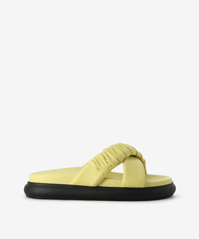 Yellow leather slides by 2 Baia Vista. It is a slip on style and features ruched cross straps, a raised padded sole, and a round toe.