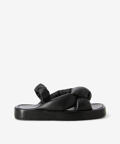 Black leather sandals by 2 Baia Vista. It is a slip-on style with an elasticated slingback that features knotted cushioned leather straps as its upper, a slight platform sole, and a square toe. 