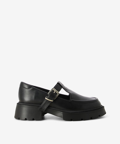 Black leather loafers by Nu by Neo. It features a strap with pin-buckle fixture, chunky tread sole, and a round toe.&nbsp;