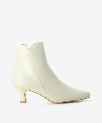 Off-white leather heeled boots by Django & Juliette. It features a side zip closure, kitten heel, and a pointed toe.
