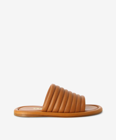 Tan leather slides by Zomp. It is a slip-on style and features a quilted-style upper, flat sole and an open round toe.