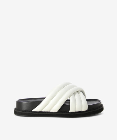 White leather cushion slides by AJ Projects. It is a slip-on style and features crossover straps, a moulded footbed and a round toe. 