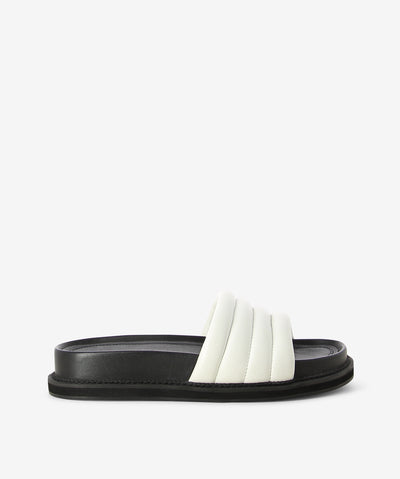 White leather cushion slides by AJ Projects. It is a slip-on style and features a padded leather band, a moulded footbed and a round toe.