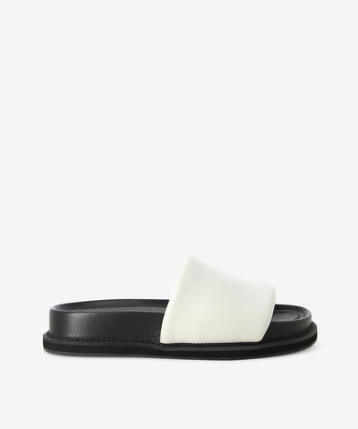 White leather cushion slides by AJ Projects. It is a slip-on style and features a padded strap, a moulded footbed and a round toe. 