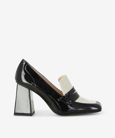 Black and off white patent leather heeled loafers by Lodi Love. It is a slip-on style and features a contrasting upper panel, block heel, and a square toe.