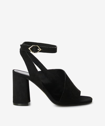 Black suede leather heels by Bruno Premi. It has an asymmetrical ankle strap and features a block heel and a square toe.