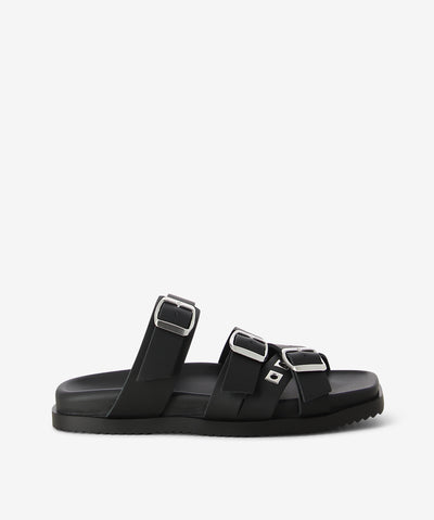 Black leather slides by Beau Coops. It is a slip-on style and features multiple buckled straps, a moulded footbed, and a square toe.