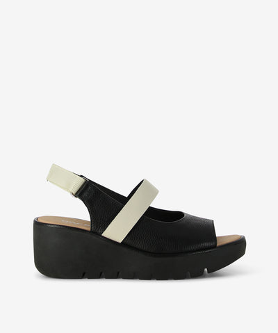 The Pollen wedge by Bresley — where modern design meets everyday comfort. Crafted with a sculptural black-toned platform and bone straps, this sandal adds a sleek, polished finish to any outfit. Featuring a peep-toe silhouette with a rounded toe and a flattering lift, dual straps for a secure fit with velcro back strap fastening, and a lightweight ridged wedge for comfort and traction. Its neutral tones pair effortlessly with everything from breezy linen to casual denim.