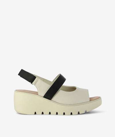 The Pollen wedge by Bresley — where modern design meets everyday comfort. Crafted with a sculptural bone-toned platform and bold black straps, this sandal adds a sleek, polished finish to any outfit. Featuring a peep-toe silhouette with a rounded toe and a flattering lift, dual straps for a secure fit with velcro back strap fastening, and a lightweight ridged wedge for comfort and traction. Its neutral tones pair effortlessly with everything from breezy linen to casual denim.