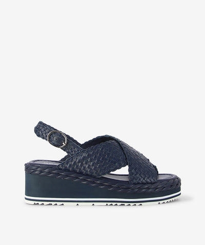 Step into easy sophistication with Scope by Bresley. Crafted in a deep navy woven leather, this sandal blends texture and comfort seamlessly. The cross-over front straps create a flattering silhouette with rounded toe, while the adjustable slingback ensures a secure fit for all-day wear. Set on a chunky wedge sole with subtle braided detailing, Scope delivers height without sacrificing comfort — perfect for laid-back weekends or casual summer days. 