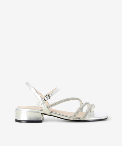 The Silver Sippa sandal by Bresley offers radiant minimalism with a touch of sparkle. Crafted in metallic silver leather, it features two rhinestone-adorned straps, a sleek ankle buckle, a low block heel for all-day comfort and a square toe. Perfect for festive nights or chic daytime looks.