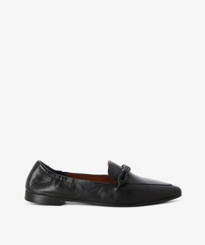 Black leather loafers by Martini Marco. It is a slip on style and features a low block heel, embellished cross strap, and a pointed toe.
