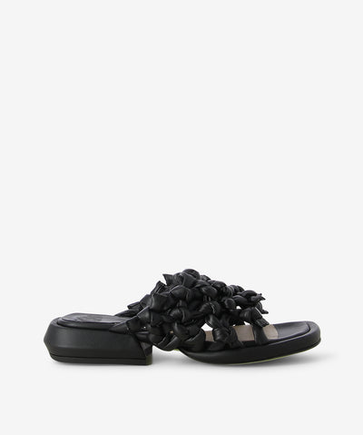 Black textured leather slides by Ixos. It features a mesh effect knotted weave, low block heel, and a soft square toe.