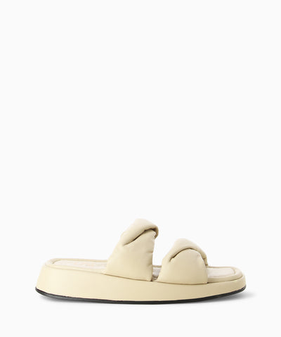 Beige leather platform slides with twisted padded straps, a cushioned insole and a soft square toe.