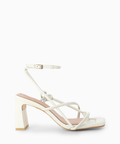 White leather heels with a wrap-around ankle strap with buckle fastening and featuring a strappy upper, slender heel, toe post and a square toe.