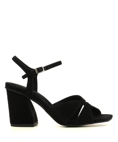 A black suede heeled sandal by Jeffrey Campbell. The 'Antique' features a cross over upper, an architectural heel and a square toe.